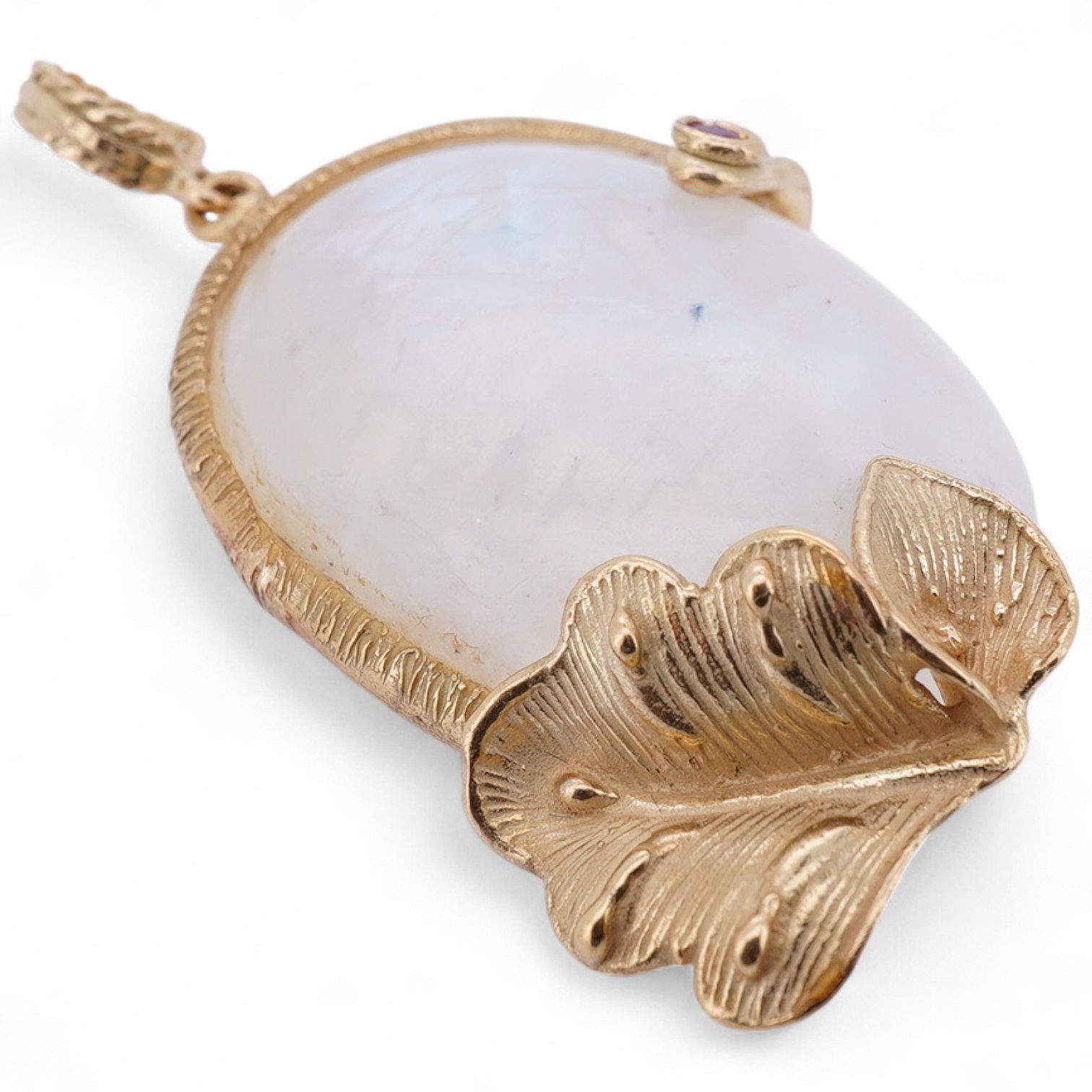 A gold and moonstone pendant, set with a moonstone cabochon, to a textured gold mount of foliate design accented with a collet-set circular-cut ruby, length 4.5cm, gross weight approximately 12 grams